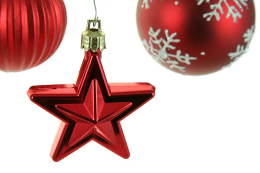 A red star Christmas ornament with two other red baubles in the back ground.
