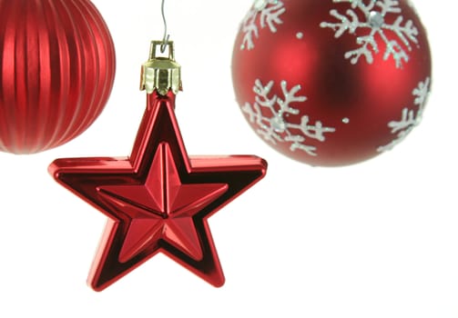 A red star Christmas ornament with two other red baubles in the back ground.
