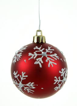 A single isolated red snowflake Christmas bauble hanging.
