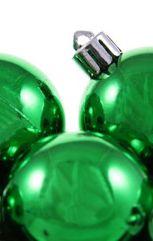 A bunch of green Christmas baubles against a white background.
