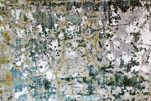 Cracked wall with fragments of old dark green paint