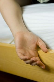 hand of a sleeping woman hanging from the bed