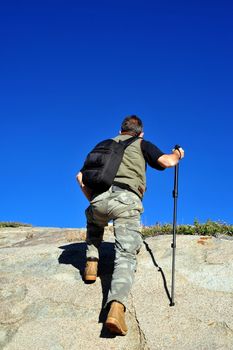 A single male day hiker reaches the summit of a granite mountain to