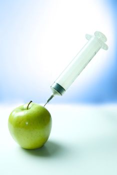 Concept image of a healthy injection, featuring a large needle being given to an apple.