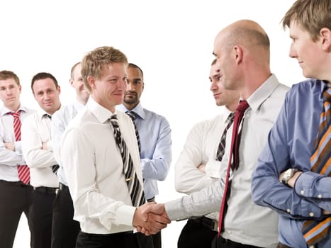 Businessmen shaking hands standing in  group of people