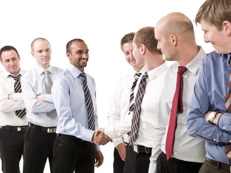 Businessmen shaking hands standing in a group of people