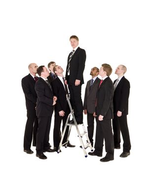 Manager standing on a step ladder with his business team around