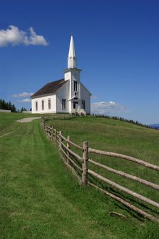 Photo of a little white wooden church in the countryside.
