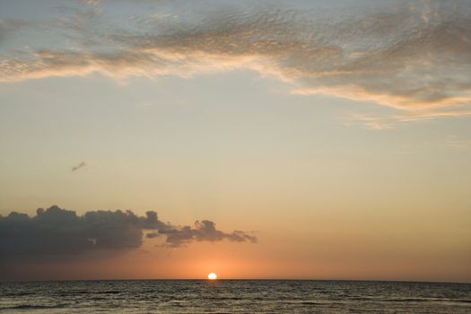 Sun rising over horizon of ocean.