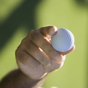 Caucasian mid adult male hand holding golf ball.