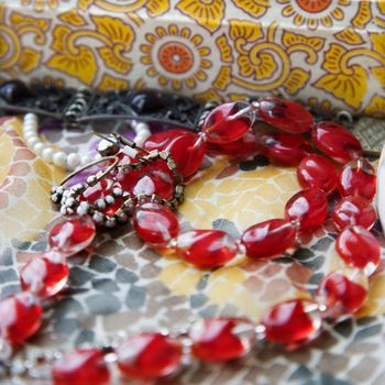 Close up of red bead necklace against pattern mosaic.