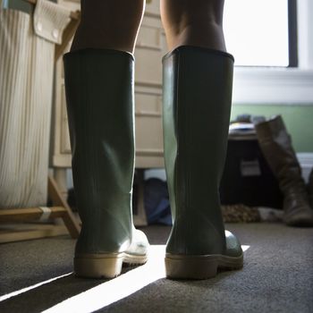 Low angle of woman's legs wearing green rubber boots.