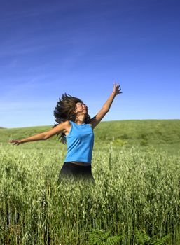  Young active woman jumping on a green field