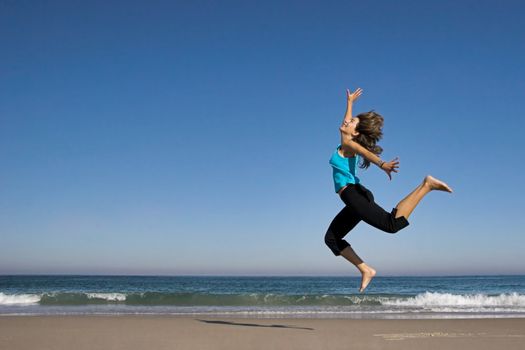 Young active woman jumping on the beach.