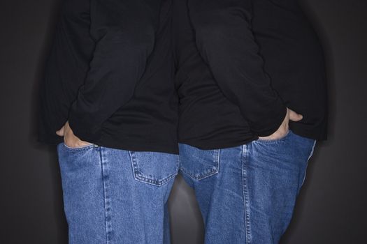 Bodies of Caucasian mid adult identical twin men standing back to back.