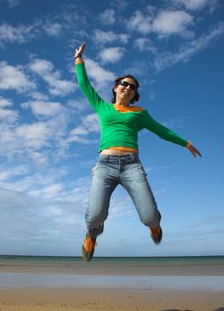 Young beautiful woman making a big jump on the beach