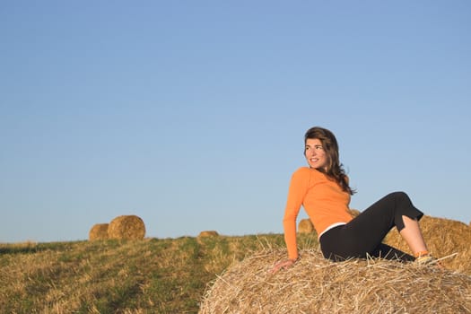 Beautiful woman in a field with hay bales