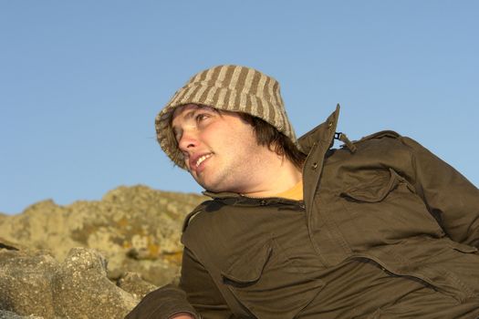 young man at the rocky beach with a hat