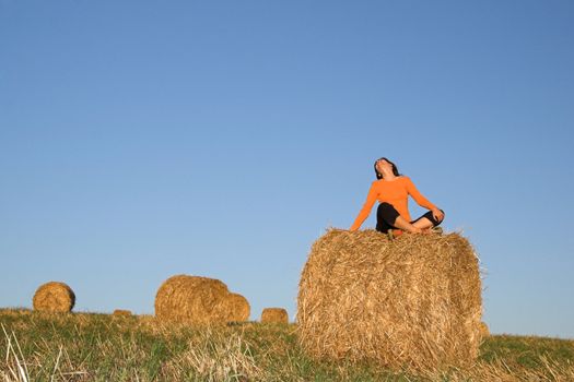 Beautiful woman seated in hay bale