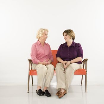 Caucasian middle aged woman and senior woman sitting conversing.