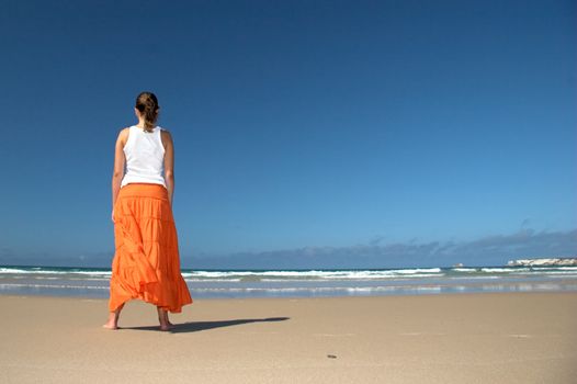 Beautiful woman in the beach with a orange skirt