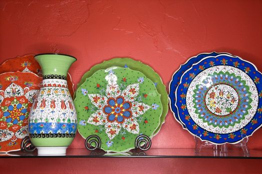 Shelf of unique plates and vases in retail store.