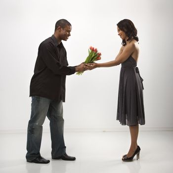 African American mid adult man giving woman bouquet of flowers.