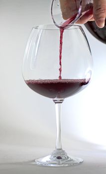 Red wine pouring from decanter to glass