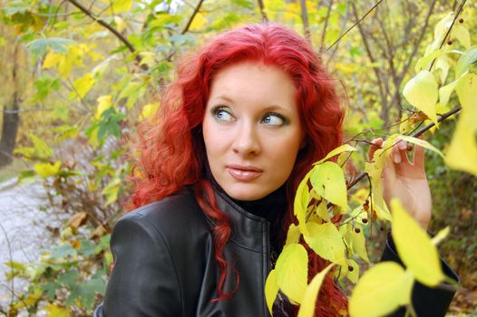 red haired gothic type girl near autumn tree