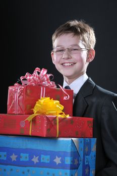 boy in a dark suit gets on the hip bright boxes with gifts