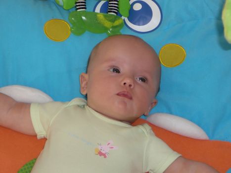 Baby girl laying on a playmat.