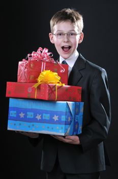 boy in a dark suit gets on the hip bright boxes with gifts