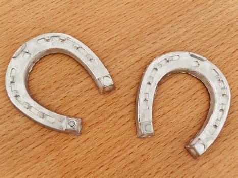 Two metal lucky horseshoes at wooden background