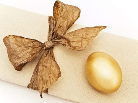 Easter decorated table serving with golden egg and bow at serviette 