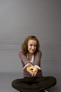portrait of a beautiful redhaired girl holding a yellow flower in her hands