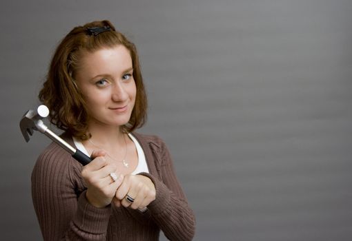 portrait of a beautiful redhaired girl holding a hammer. Be careful!