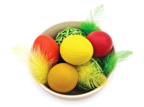different easter eggs and feathers in the bowl against white background