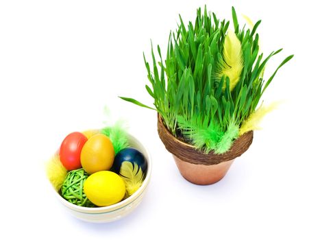 bowl with colored easter eggs and flower pot with green grass