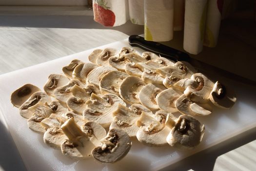 Mushrooms sliced on a cutting board, lit with natural light from a kitchen window