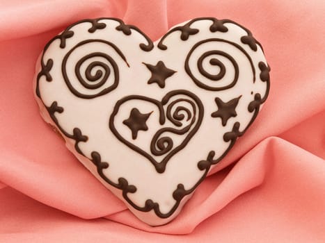 Photo of spice cake in heart shape at pink textile drapery