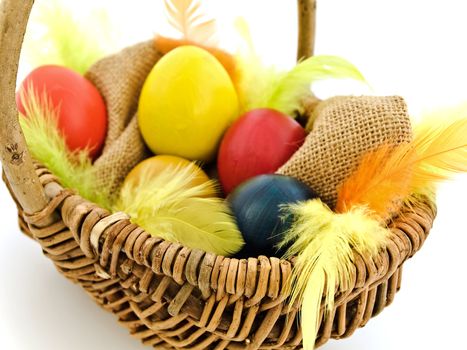 multicolored easter eggs and feathers in the basket