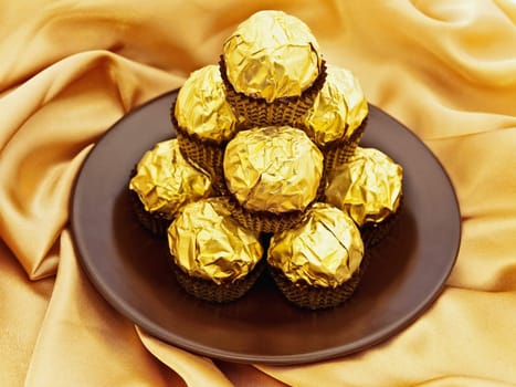 confection heap on the saucer over golden textile background 
