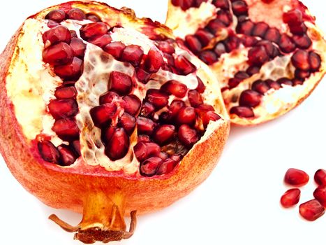 broken red pomegranate and seeds against white background 