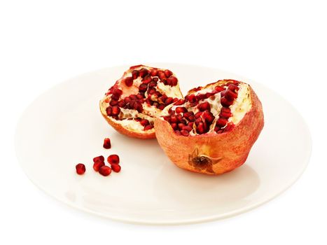 pomegranate in pieces at plate over white background