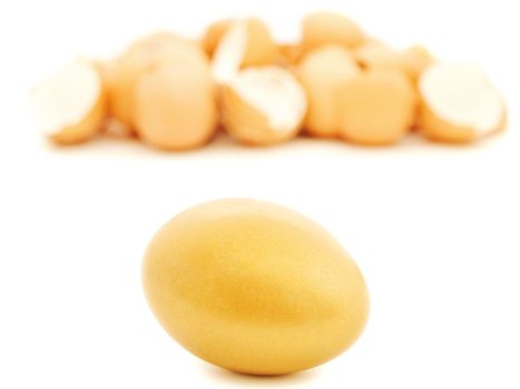golden egg at white against heap of egg shell 