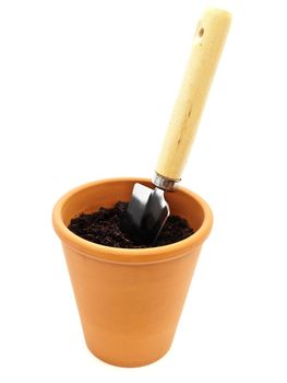 Gardening trowel in pot with black soil against white background