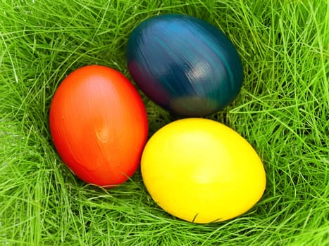 three  multicolored eastern eggs in fresh green grass