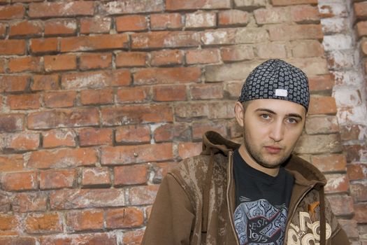 Rapper boy posing at a brick wall, urban scene