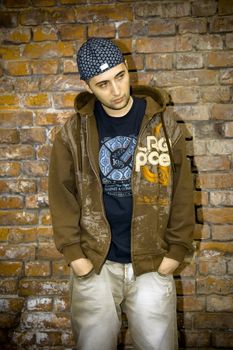 Rapper boy posing at a brick wall, urban scene