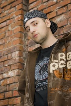Rapper boy posing at a brick wall, urban scene